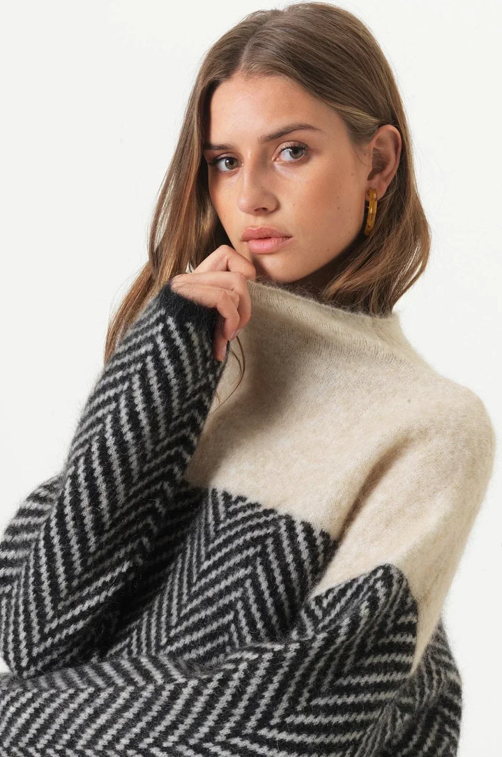 Hyggelig damestriktrøje med farveblok mønster og høj hals. Komfortabel sweater til kolde dage.