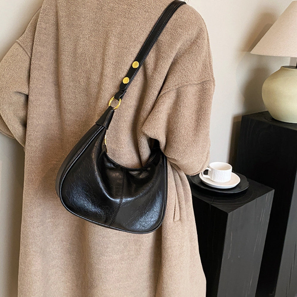 Elegant crossbodytaske med justerbar rem og guldfarvede detaljer, ideel til hverdagsbrug.