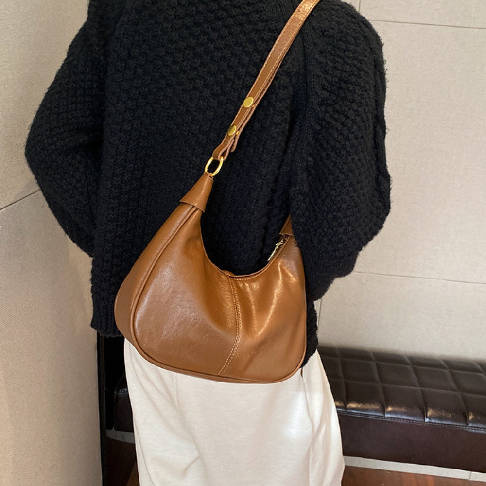 Elegant crossbodytaske med justerbar rem og guldfarvede detaljer, ideel til hverdagsbrug.
