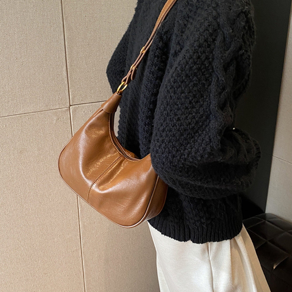 Elegant crossbodytaske med justerbar rem og guldfarvede detaljer, ideel til hverdagsbrug.