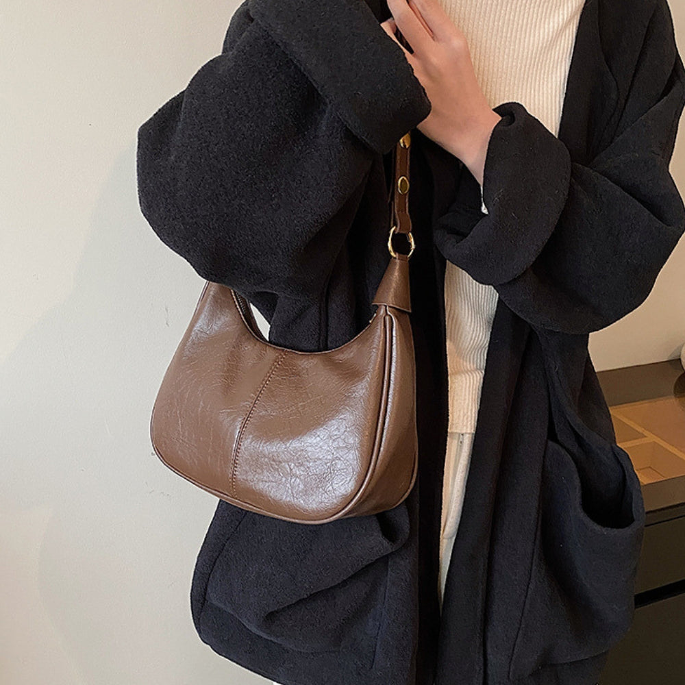 Elegant crossbodytaske med justerbar rem og guldfarvede detaljer, ideel til hverdagsbrug.
