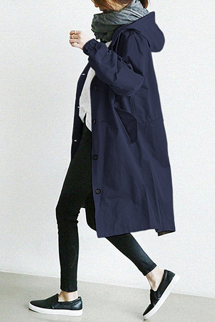 Modebevidst dame regnfrakke. Vandtæt trenchcoat med beskyttende hætte. Elegant overtøj til forår/efterår.