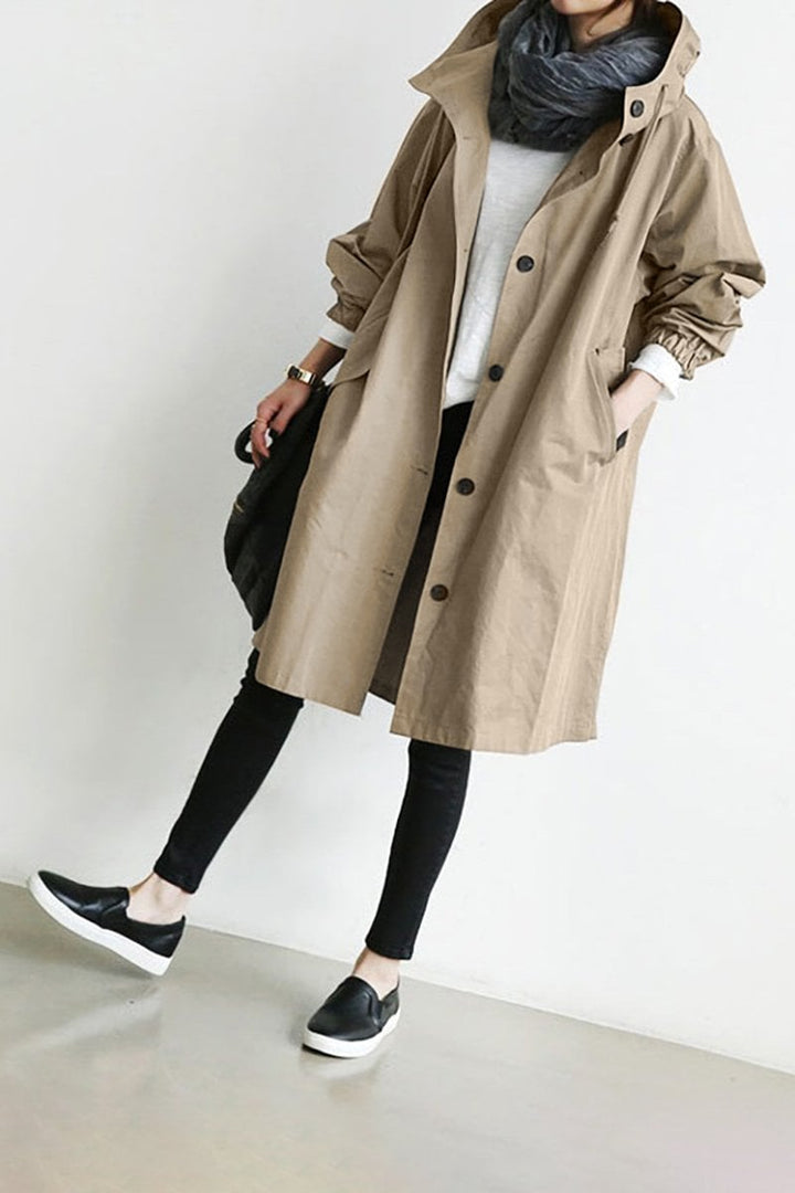 Stilfuld dame regn trenchcoat med hætte. Lang, vandtæt frakke der beskytter mod vind og regn. Klassisk look.