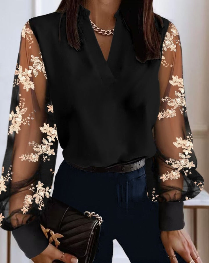 Elegant damebluse med gennemsigtige ærmer og smukt blomsterbroderi. Perfekt til fest og aftenbrug.