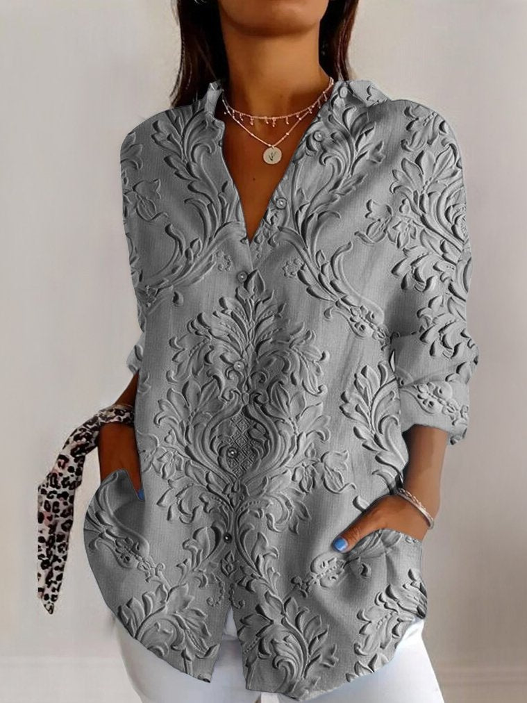 Grå damebluse med unikt præget blomsterdesign. Komfortabel langærmet med v-udskæring, ideel til elegant hverdag.
