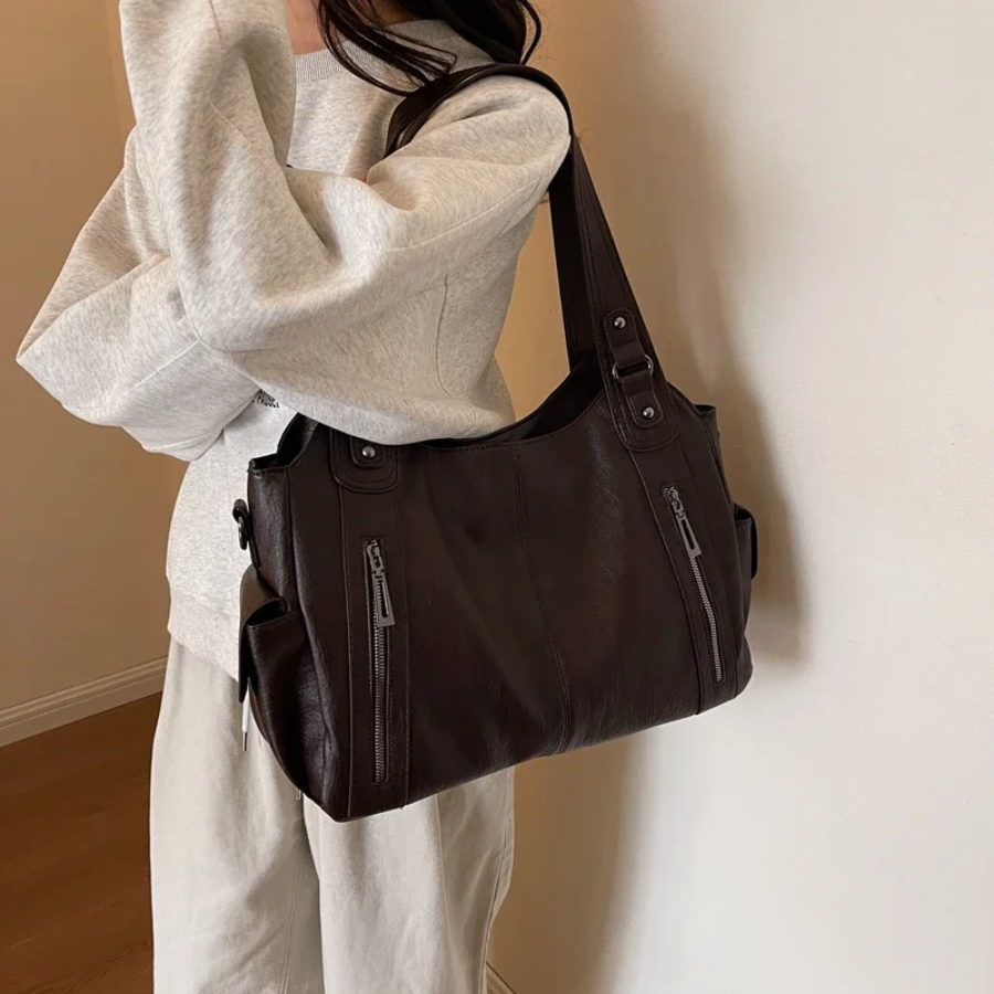 "Elegant kvinders skuldertaske i sort med justerbar rem og metaldekorationer, ideel til både hverdag og formelle lejligheder.