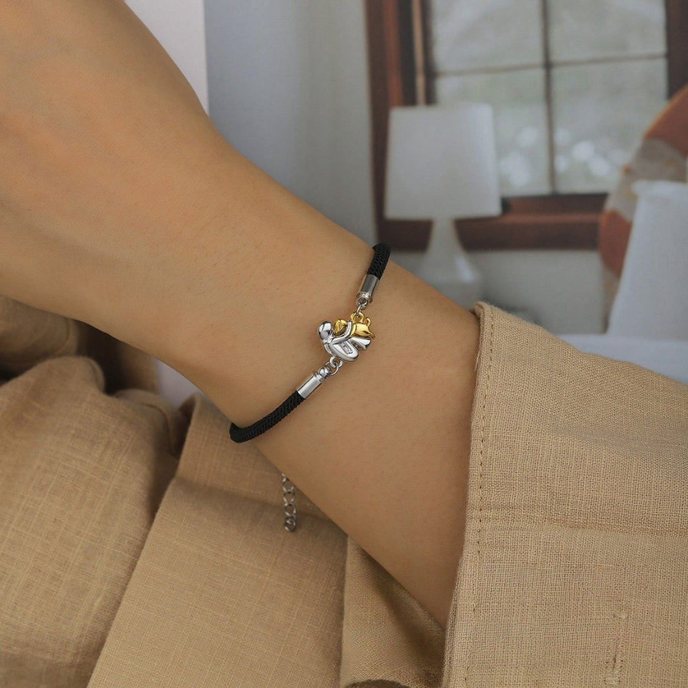 Moderne damearmbånd med minimalistisk design. Sort bånd og diskrete guld charms for et elegant look.