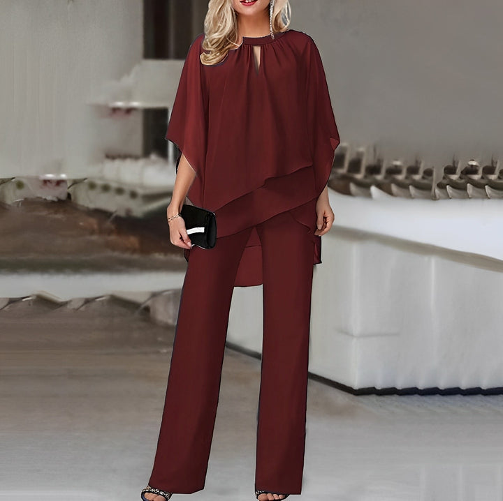 Elegant vinrød buksedragt til kvinder med asymmetrisk top. Perfekt til fest og aftenoutfit.