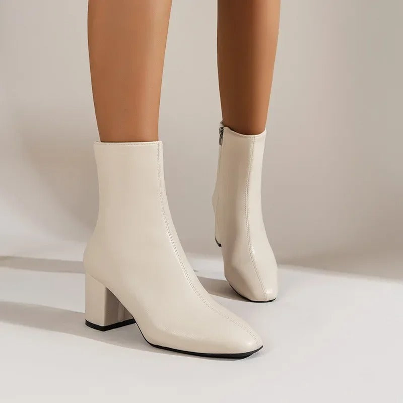 Nærbillede af blank lakfinish og stabil blokhæl på en elegant dames ankelstøvle. Kvalitets modefodtøj.