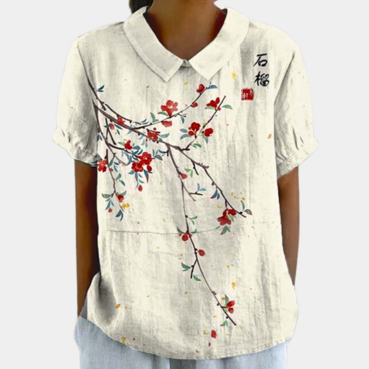 Levende damebluse med blomstermønster og rund krave, ideel til sommer. En stilfuld opgradering til enhver garderobe.