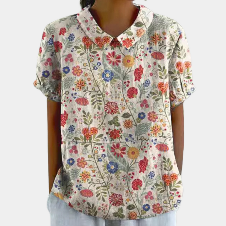 Levende damebluse med blomstermønster og rund krave, ideel til sommer. En stilfuld opgradering til enhver garderobe.