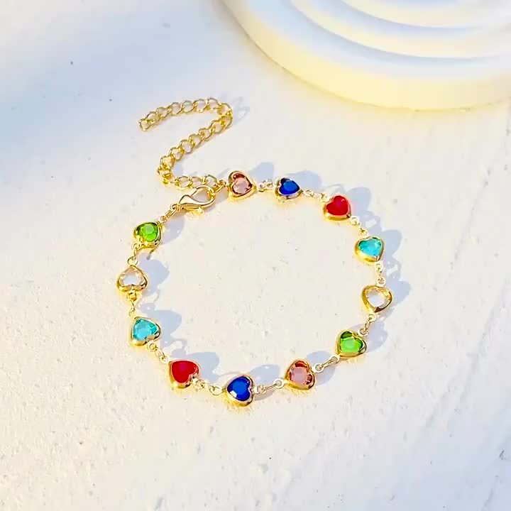 Moderigtigt damearmbånd med farverige krystalhjerter og elegant finish i guld eller sølv.