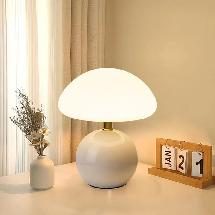 "Flødefarvet svampeinspireret bordlampe med Bauhaus-æstetik, cremefarvet skærm og elegant keramisk base."