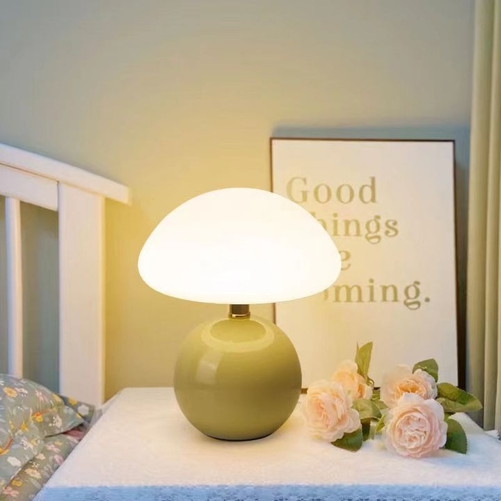 "Flødefarvet svampeinspireret bordlampe med Bauhaus-æstetik, cremefarvet skærm og elegant keramisk base."