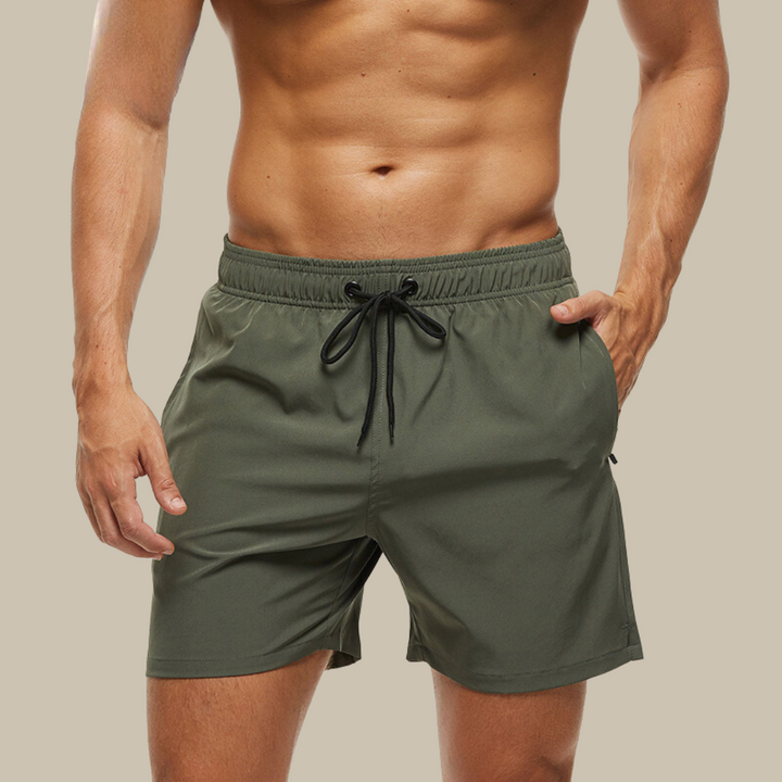 Hurtigtørrende herrebadeshorts med lynlåslommer og elastisk pasform, set forfra.