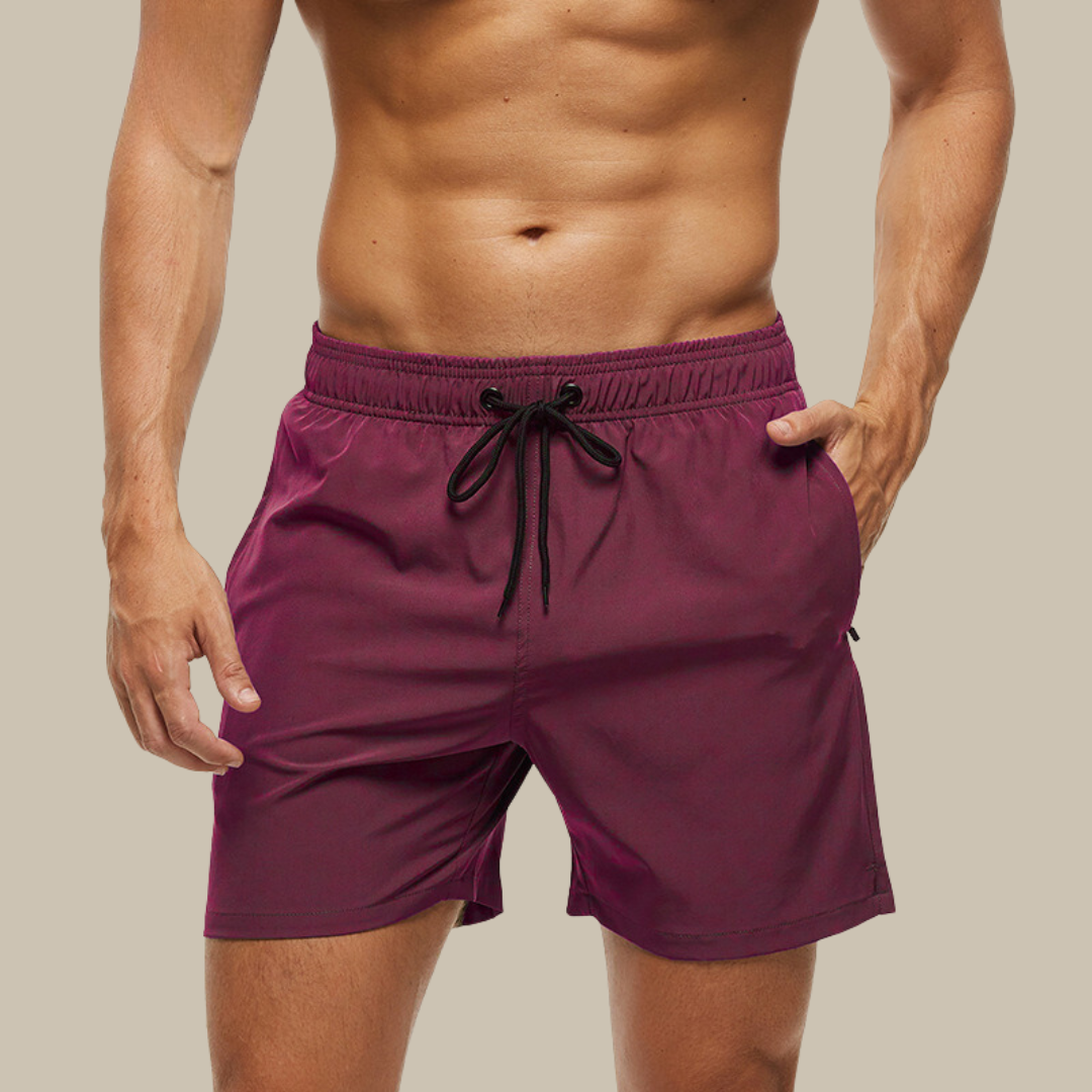 Hurtigtørrende herrebadeshorts med lynlåslommer og elastisk pasform, set forfra.