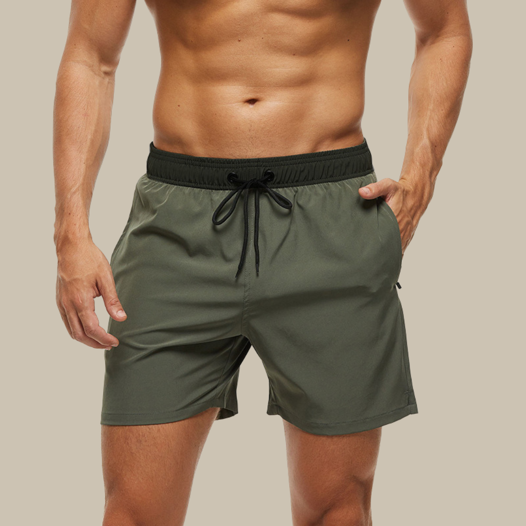 Hurtigtørrende herrebadeshorts med lynlåslommer og elastisk pasform, set forfra.