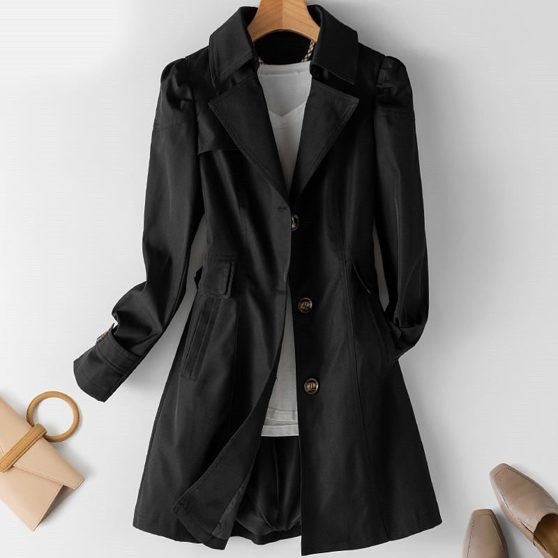 Kvindelig trenchcoat i beige med klassisk snit, knaplukning, letvægts og vandafvisende materiale. Set forfra mod baggrund.