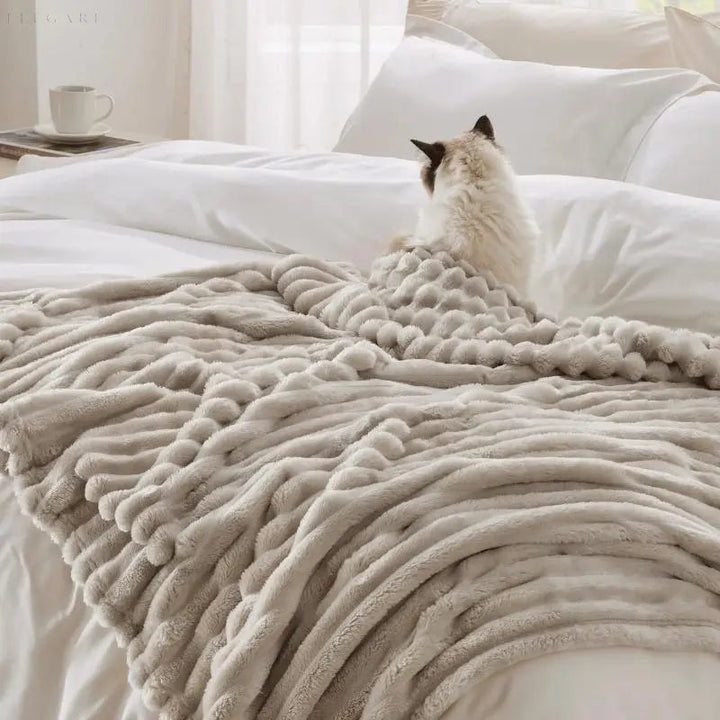 "Luksuriøst plysset fleece tæppe i blød beige. Perfekt til sofa eller seng for ekstra varme og hygge, fås i flere størrelser.