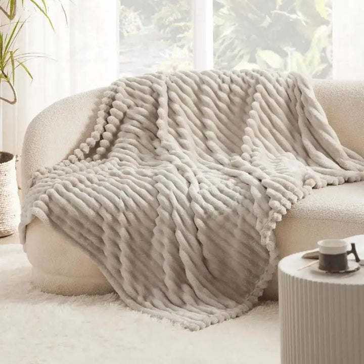 "Luksuriøst plysset fleece tæppe i blød beige. Perfekt til sofa eller seng for ekstra varme og hygge, fås i flere størrelser.