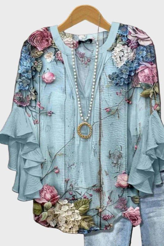 Lyseblå damebluse med blomsterprint og flæser for et feminint, komfortabelt look.