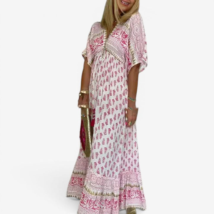 Lyserød dame maxikjole med løs pasform, elegant v-hals og trendy kvaster, perfekt til sommerferie.