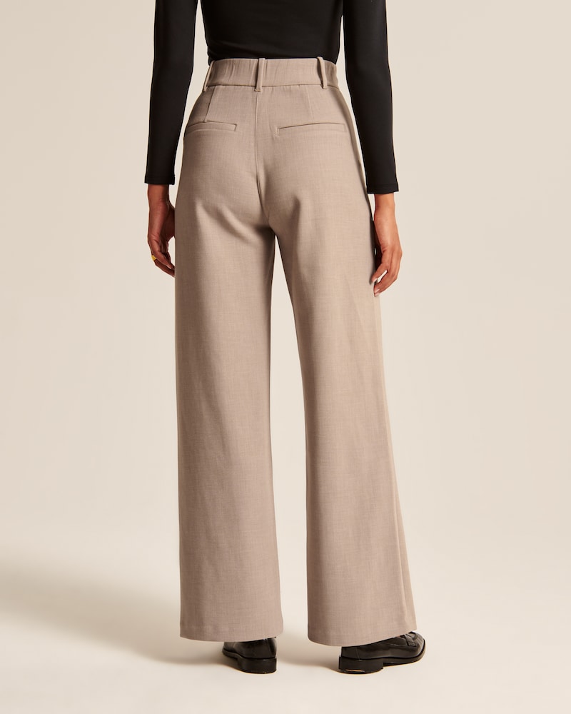 "Model iført beige polyester bukser med høj talje og bredde ben, ideel til professionelt og tidløst look."