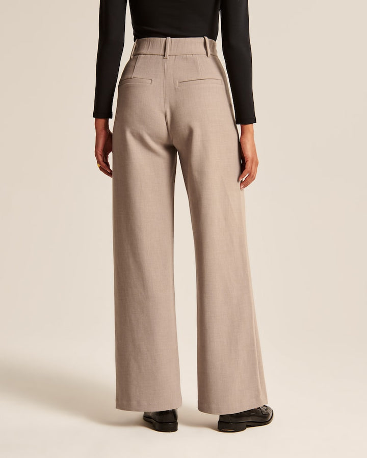 "Model iført beige polyester bukser med høj talje og bredde ben, ideel til professionelt og tidløst look."