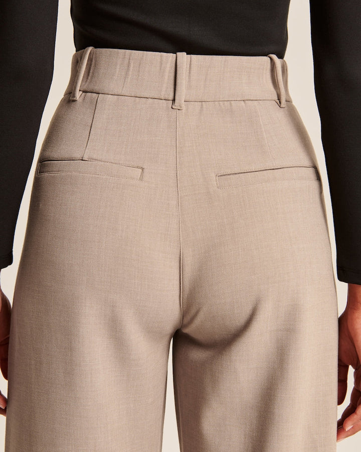 "Model iført beige polyester bukser med høj talje og bredde ben, ideel til professionelt og tidløst look."